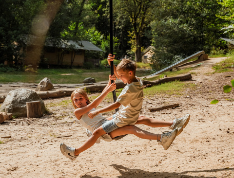Deux enfants jouent sur une tyrolienne à Buitenplaats Beekhuizen - Glamping Veluwe, en pleine nature.