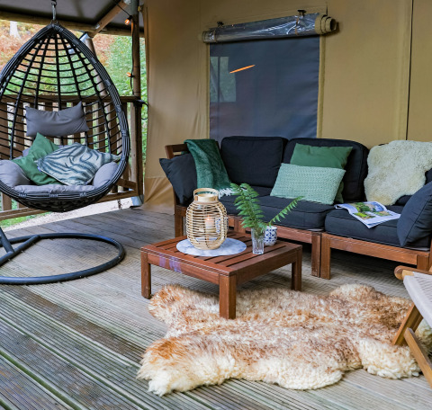 Gemütliche Lounge im Glamping-Zelt bei Buitenplaats Beekhuizen Veluwe mit Hängesessel und Sofaecke.