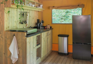 Sfeervol keukentje bij Buitenplaats Beekhuizen - Glamping Veluwe met houten kastjes en moderne koelkast.