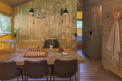 Hébergement glamping accueillant avec intérieur en bois, table à manger, jeu d'échecs et ambiance cosy.