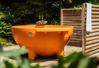 Rond oranje buitenbad met twee glazen wijn en handdoek, glamping bij Buitenplaats Beekhuizen Veluwe.