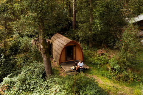 To personer sidder foran en glamping-hytte hos Buitenplaats Beekhuizen - Glamping Veluwe omgivet af skov.