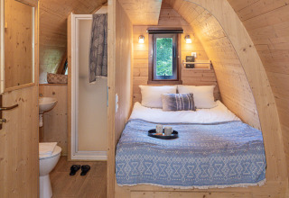Hébergement glamping confortable à Buitenplaats Beekhuizen, Veluwe, avec lit double et salle de bain en bois.