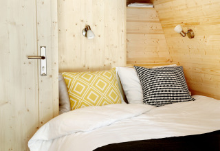 Knusse glamping accommodatie bij Buitenplaats Beekhuizen - Glamping Veluwe met houten wanden en kussens.