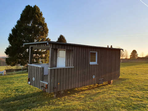 Glamping accommodatie in een houten wagen bij Camping im Bergischen Land, Noordrijn-Westfalen bij zonsopgang.