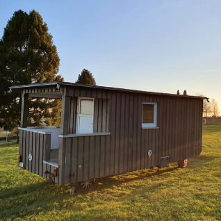 Glamping accommodatie in een houten wagen bij Camping im Bergischen Land, Noordrijn-Westfalen bij zonsopgang.
