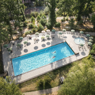 Vista aerea di una piscina, lettini e ombrelloni tra gli alberi all'Huttopia Wattwiller Glamping Grand Est.
