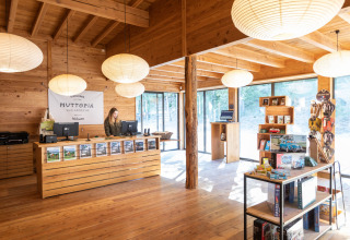 Zona de recepción en Huttopia Wattwiller - Glamping Grand Est con decoración de madera y souvenirs en venta.