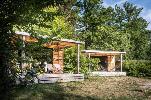 Cozy wooden glamping cabins surrounded by lush trees at Huttopia Wattwiller - Glamping Grand Est.