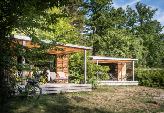 Billedet viser hyggelige træhytter omgivet af skov ved Huttopia Wattwiller - Glamping Grand Est.