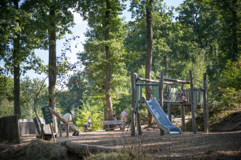 Aire de jeux enfant au cœur des arbres à Huttopia Wattwiller - Glamping Grand Est, lieu de camping familial.