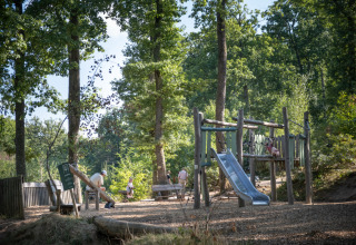 Área de juegos infantiles entre árboles en Huttopia Wattwiller - Glamping Grand Est, camping ideal familiar.