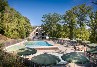 Piscina all'aperto con ombrelloni verdi e ospiti a Huttopia Wattwiller - Glamping Grand Est.