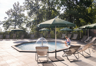 Piscine extérieure avec parasols verts et transats au Huttopia Wattwiller Glamping Grand Est.