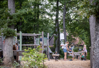Børn leger på legeplads omgivet af træer ved Huttopia Wattwiller - Glamping Grand Est campingplads.
