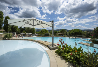 Udendørs swimmingpool med parasoller, blomster og bjerge i baggrunden på Domaine de Sévenier & Spa, Auvergne-Rhône-Alpes.