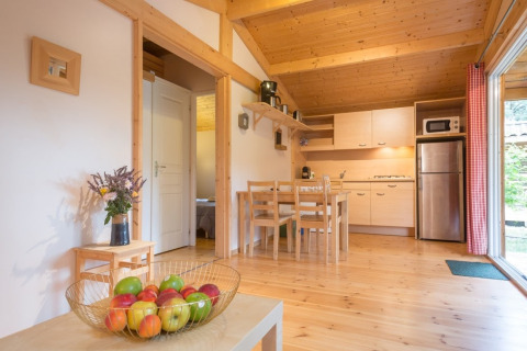 Innenraumfoto eines Holzchalets mit moderner Küche, Esstisch und Obstschale im Domaine de Sévenier & Spa.