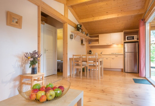 Interieur van een houten chalet met keuken, eetgedeelte en fruitschaal bij Domaine de Sévenier & Spa.