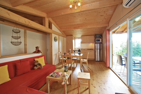 Interior view of Domaine de Sévenier & Spa glamping chalet featuring wood furnishings and open kitchen.