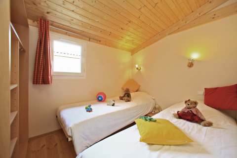 Dormitorio infantil con dos camas individuales, juguetes y peluches en un chalet de Domaine de Sévenier & Spa.