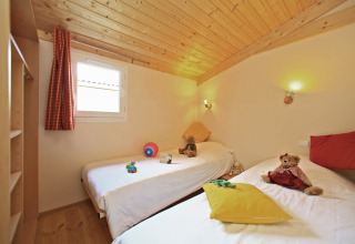 Camera per bambini con due letti singoli, giocattoli e peluche in uno chalet al Domaine de Sévenier & Spa.