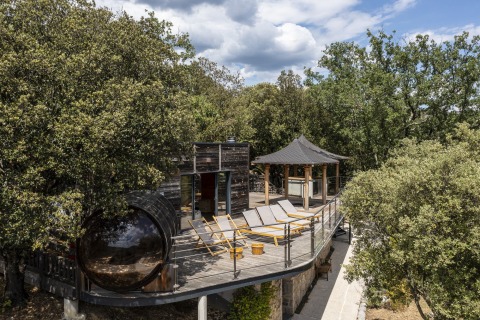 Terrazza con sdraio, chalet in legno e spa immersi nel verde al Domaine de Sévenier & Spa in Francia.