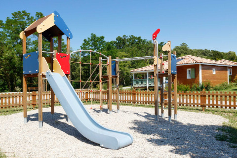 Playground with slide and chalet accommodation at Domaine de Sévenier & Spa in Auvergne-Rhône-Alpes, France.