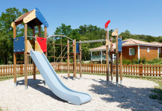 Spielplatz mit Rutsche und Chalet-Unterkünften im Domaine de Sévenier & Spa in Auvergne-Rhône-Alpes, Frankreich.