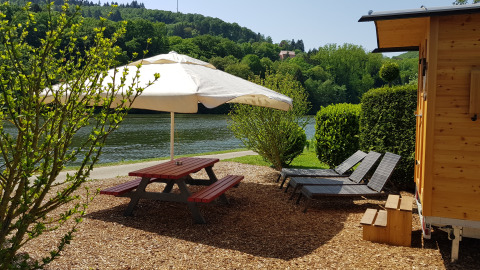 Glamping al Camping Fortuna am Neckar con tavolo da picnic, lettini e roulotte vicino al fiume in Baden-Württemberg.