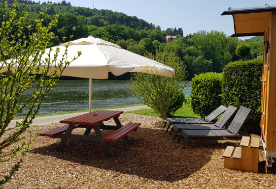 Glamping ved floden på Camping Fortuna am Neckar med picnicbord, liggestole og zigeunerwagen i Baden-Württemberg.