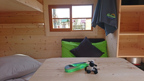 Indretning af glampingvogn på Camping Fortuna am Neckar i Baden-Württemberg med træinteriør og farverige puder.