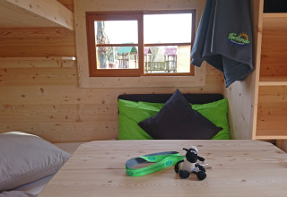 Indretning af glampingvogn på Camping Fortuna am Neckar i Baden-Württemberg med træinteriør og farverige puder.