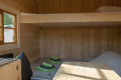 Intérieur d'un logement glamping en bois au Camping Fortuna am Neckar, avec lits superposés et serviettes pliées.