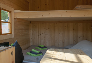 Interior acogedor de glamping en Camping Fortuna am Neckar con literas y toallas dobladas sobre la cama.