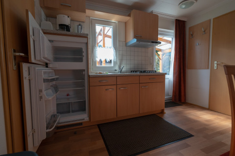 Intérieur d'une cuisine de camping au Camping Hetzingen - Stacaravans avec meubles en bois et frigo ouvert.
