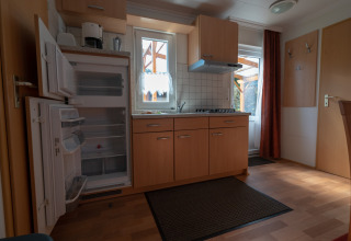 Innenansicht einer gemütlichen Campingküche bei Camping Hetzingen - Stacaravans mit offenem Kühlschrank.