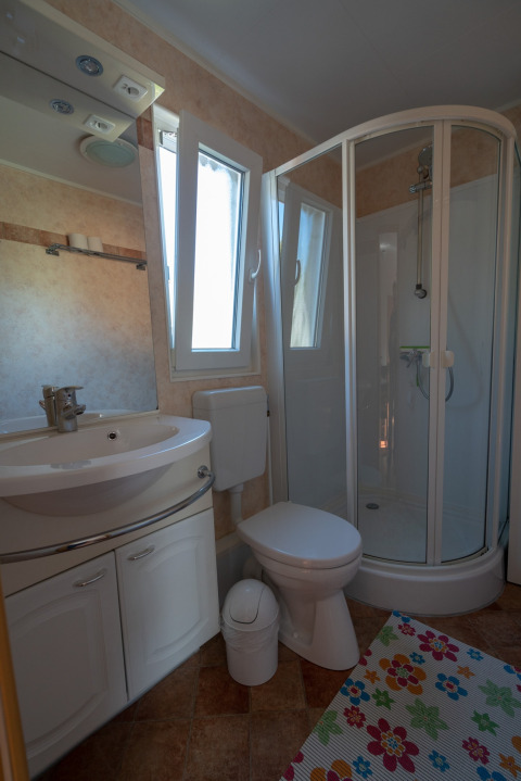 Salle de bain de camping moderne avec douche, WC, lavabo et tapis coloré au Camping Hetzingen, Rhénanie-du-Nord-Westphalie.