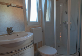 Moderne campingbadeværelse med bruser, toilet, håndvask og blomstrede gulvmåtte på Camping Hetzingen.