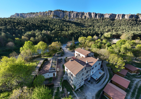 Luchtbeeld van Huttopia Barcelona Pirineos - Glamping Catalonië tussen bos en rotsachtige heuvelrug.