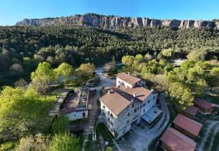 Luftfoto af Huttopia Barcelona Pirineos - Glamping Catalonië, omgivet af frodigt grønt og bjergrig natur.