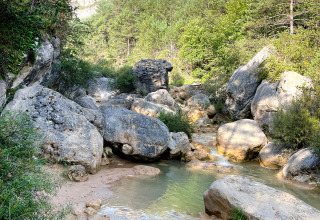 Felsen, Fluss und bewaldete Berge bei Huttopia Barcelona Pirineos - Glamping Catalonië unter blauem Himmel.
