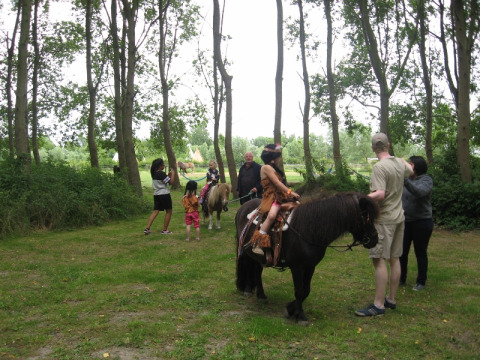 Børn og voksne hygger sig på en ponytur i en skov nær glampingpladsen De Bokkesprong i Holland.