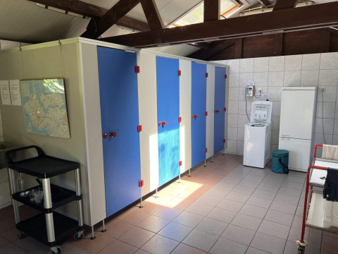 Espace commun intérieur chez Glamping De Bokkesprong avec cabines bleues, lave-linge et carte murale.