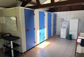 Gemeenschappelijke binnenruimte van glamping De Bokkesprong met cabines, wasmachine en wandkaart.