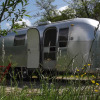 Airstream Hotel - Vintage Caravan Thüringen glamping trailer in nature, surrounded by wildflowers and trees.