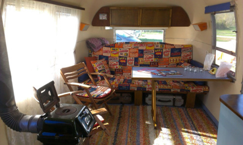 Indvendig i en vintage campingvogn med farverige puder og et bord, del af Airstream Hotel i Thüringen.