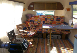 Interior of a vintage caravan with colorful cushions and table, part of the Airstream Hotel in Thuringia.