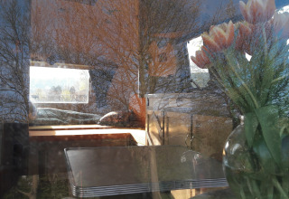 Vue intérieure d’un glamping à l’Airstream Hotel - Vintage Caravan Thüringen avec des reflets d’arbres extérieurs.