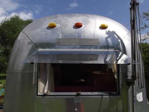 Vista anteriore di una roulotte Airstream d’epoca usata come alloggio glamping con finestra aperta in Turingia.