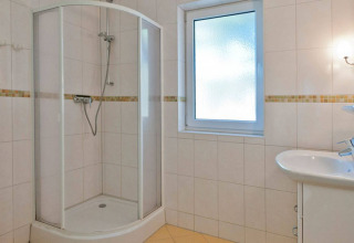 Modern bathroom with shower, sink and frosted window in glamping accommodation at Vakantiepark Havelberge.